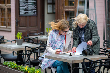 Two business women in an outdoor cafe closed the deal and sign the documents.の写真素材