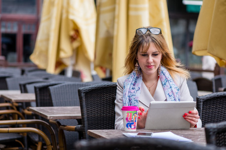 A young business woman drinking tea in a cafe and working with a computer. の写真素材