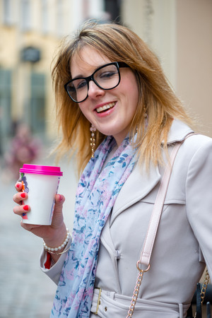 Beautiful young woman with hot tea in a paper mug.の写真素材