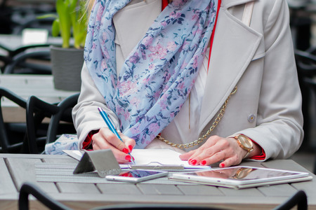 Beautiful young business woman sitting in an outdoor cafe and working with documents.の写真素材