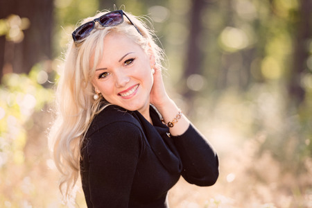 A young, blond and smiling woman portrait on a sunny autumn day.の写真素材