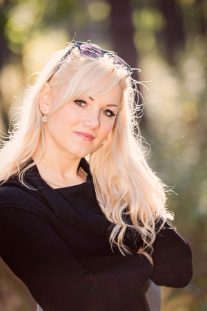 A young, blond and smiling woman portrait on a sunny autumn day.の写真素材