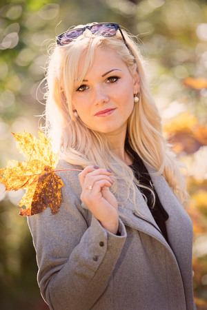 A young, blonde and smiling woman portrait on a sunny autumn day.の写真素材