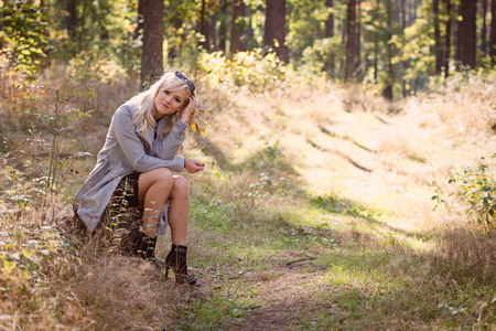 A young, blonde woman walking through the forest on a sunny autumn day.の写真素材