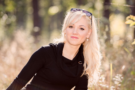 A young, blonde and smiling woman portrait on a sunny autumn day.の写真素材