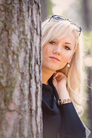 A young, blonde woman walking through the forest on a sunny autumn day.の写真素材