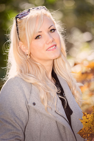 A young, blonde and smiling woman portrait on a sunny autumn day.の写真素材