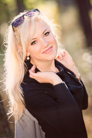 A young, blonde and smiling woman portrait on a sunny autumn day.の写真素材