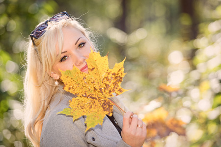 A young, blonde and smiling woman portrait on a sunny autumn day.の写真素材