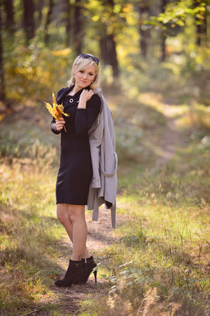 A young, blonde woman walking through the forest on a sunny autumn day.の写真素材