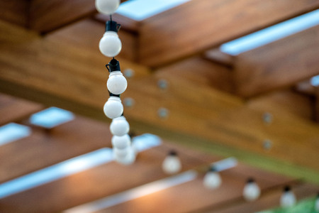 Garland of light bulbs hanging under the ceiling in a wooden houseの写真素材