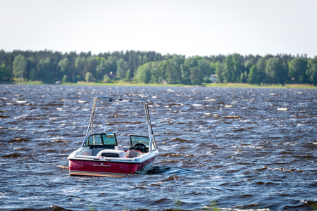 A red-white motorboat is rocking at the waves of the lake.の写真素材
