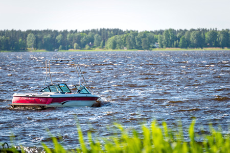 A red-white motorboat is rocking at the waves of the lake.の写真素材
