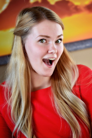 Surprised and excited blonde woman in a red dress.の写真素材
