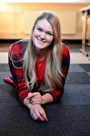 A smiling blonde woman in a red checkered shirt lying on the floor.の写真素材