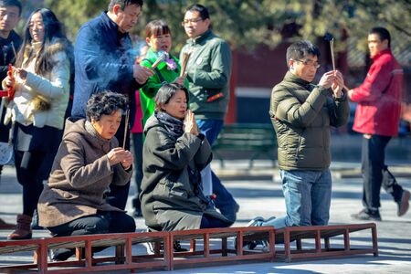 BEIJING, CHINA - MARCH 10, 2016: Worshippers hold incense sticks and pray at Yonghegong Lama Temple in Beijing, China.のeditorial素材