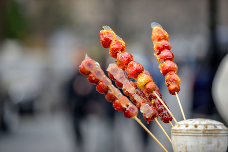 stall with caramelized fruit on stick on street Qianmen in Beijing city. Qianmen Street runs south from Tiananmen Square, just along the Beijing central axisの写真素材