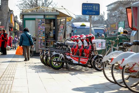 BEIJING, CHINA - MARCH 14, 2016: People are walking and driving through the streets with bicycles, scooters and cars.のeditorial素材