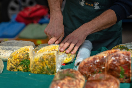 The man with the knife cuts the cheese market on the table.の写真素材