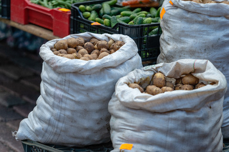 The market sells a variety of vegetables and bags with potatoes.の写真素材