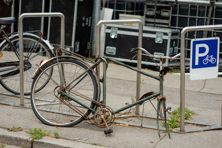 A damaged bike is locked in a bicycle stand.の写真素材