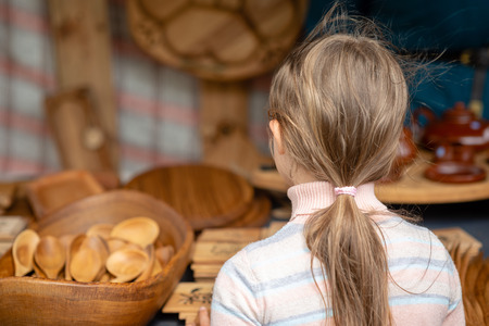 The girl is looking at wood products on the market. View from the back.の写真素材