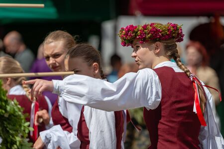 RIGA, LATVIA - JUNE 22, 2018: Summer solstice market. A young woman dressed in a national costume, with a hand pointing to an interesting view.のeditorial素材