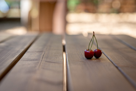 A bunch of cherries on a wooden table surface.の写真素材