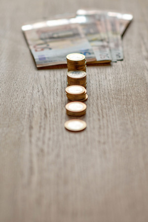 Selective focus photograph. Stack with 1 euro coins and banknotes in the background.の写真素材