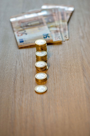 Selective focus photograph. Stack with 1 euro coins and banknotes in the background.の写真素材