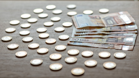50 euro banknotes and 1 euro coins on a light wood background.の写真素材