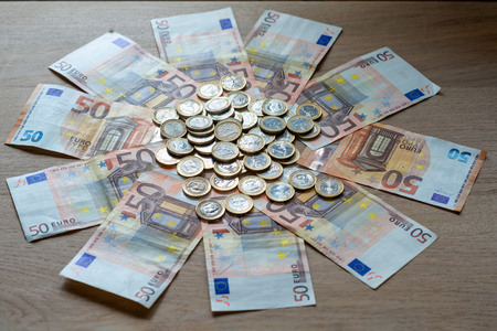 50 euro banknotes and 1 euro coins on a light wood background.の写真素材