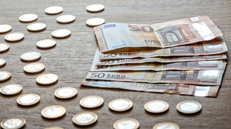 50 euro banknotes and 1 euro coins on a light wood background.の写真素材