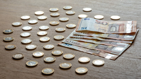 50 euro banknotes and 1 euro coins on a light wood background.の写真素材