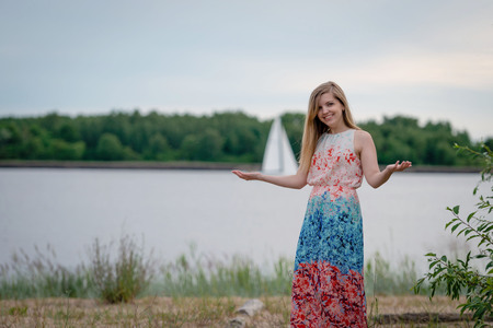 A young woman wearing a colorful long dress standing at the edge of the canal and gesticulate with her hands.の写真素材