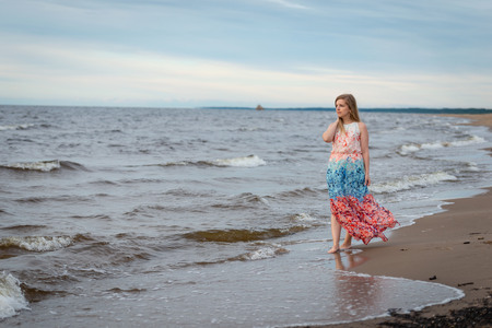 A young woman walking in the colorful long gown along the seafront.の写真素材