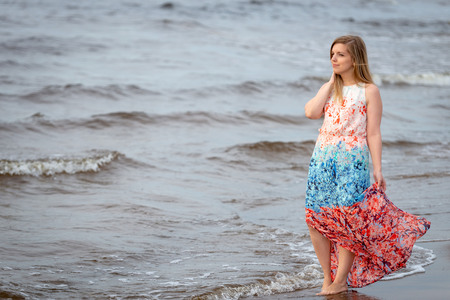 A young woman walking in the colorful long gown along the seafront.の写真素材