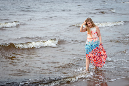 A young woman walking in the colorful long gown along the seafront.の写真素材