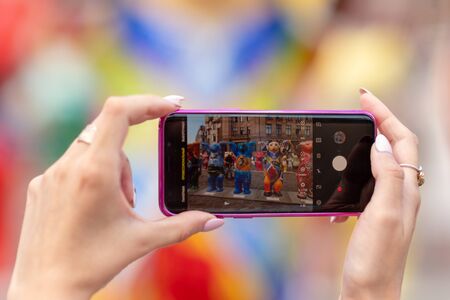 RIGA, LATVIA - JULY 26, 2018: United Buddy Bears exhibition. A woman with a phone takes pictures of bear sculptures.のeditorial素材