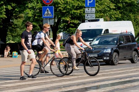 RIGA, LATVIA - JULY 18, 2018: Cyclists and pedestrians cross the street through a pedestrian...