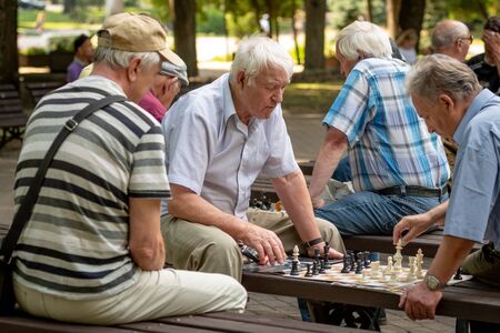 RIGA, LATVIA - JULY 18, 2018: Men seated on park benches and playing chess.のeditorial素材