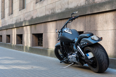 Black motorcycle with large tires on the sidewalk.の写真素材