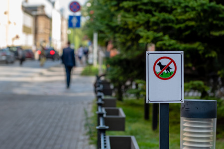 Set on the side of the street is a sign that forbids dogs to roam the green area.