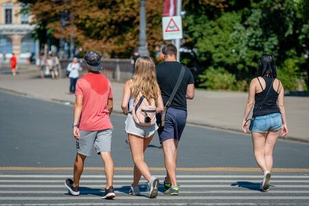 RIGA, LATVIA - JULY 31, 2018: Pedestrians cross the street through a pedestrian crossing.