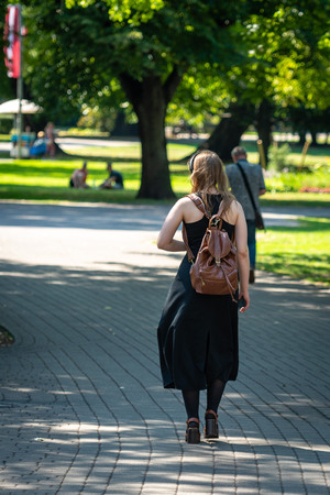 Girl with a backpack walking along the city park.の写真素材