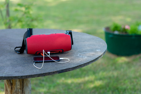 Smartphone with portable speakers is placed on a wooden table.の写真素材