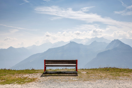 A wooden bench at the top of the Alps, a place for tourists to relax and look at beautiful landscapes.の写真素材