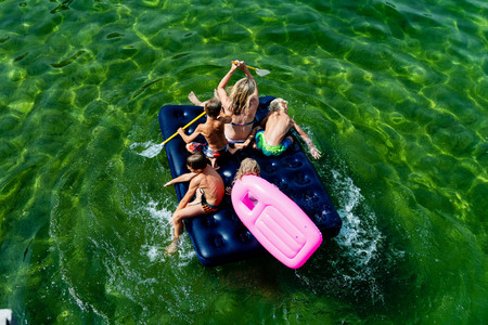 Happy family with children is swimming and having fun in the sea on an inflatable mattress. Happy friendly family concept. Aerial view.の写真素材