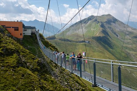 BAD GASTEIN, AUSTRIA - AUGUST 06, 2018: People cross a suspension bridge on the Stubnerkogel, Gastein mountains, Austria, Europe.のeditorial素材