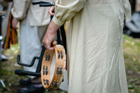 A woman in national costume holds a tambourine in her hands.の写真素材